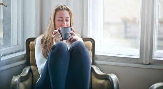 Femme assise dans fauteuil dans son salon au chaud grâce a une bonne isolation