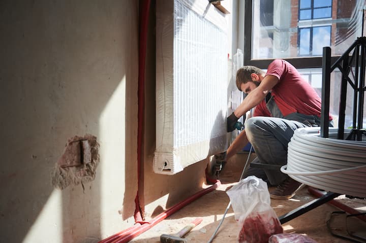 Chantier avec un artisan qui installe un radiateur à inertie