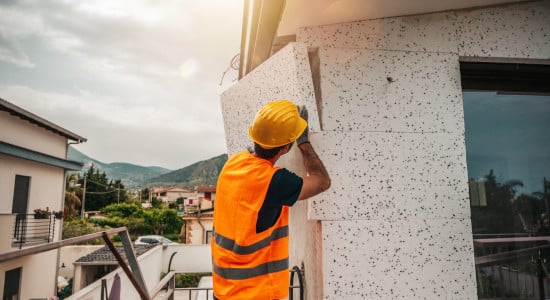 Pose de panneaux d'isolant en polystyrène sur la façade extérieur d'une maison