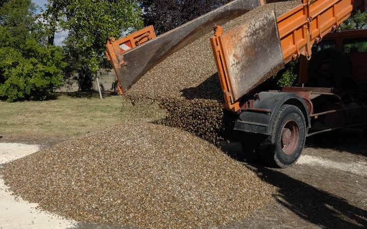 Camion-benne basculante qui dépose du gravier pour l'aménagement extérieur d'un jardin