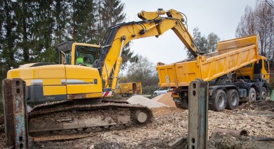 Grue et benne basculante qui débarrassent les déchets d'un chantier de démolition d'une maison