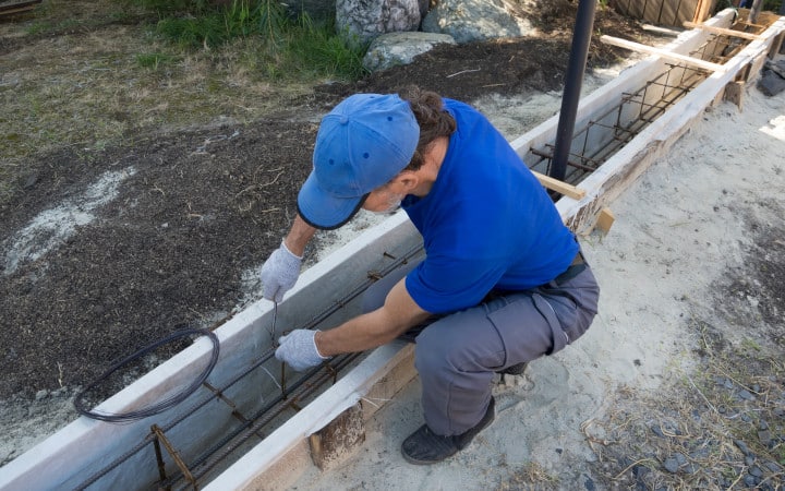 Artisan qui pose les fondations d'un mur de clôture