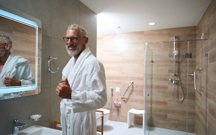Homme à la retraite dans une salle de bain adaptée suite à des travaux de rénovation pour adapter le logement au vieillissement