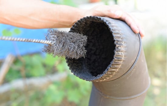 Nettoyage du bistre dans le tubage d'une cheminée à l'aide d'une brosse métallique