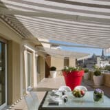 Store banne couvrant une terrasse et fixé sur un mur avec isolation extérieure